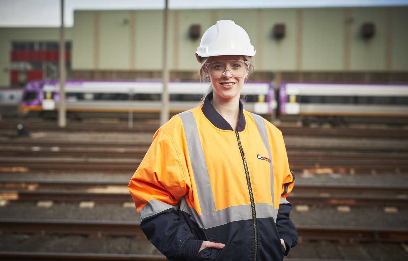 A rail worker standing in front of a train on the tracks, representing the Rail Career Path Program